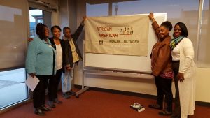 A group of five African American women holding up a banner that reads 