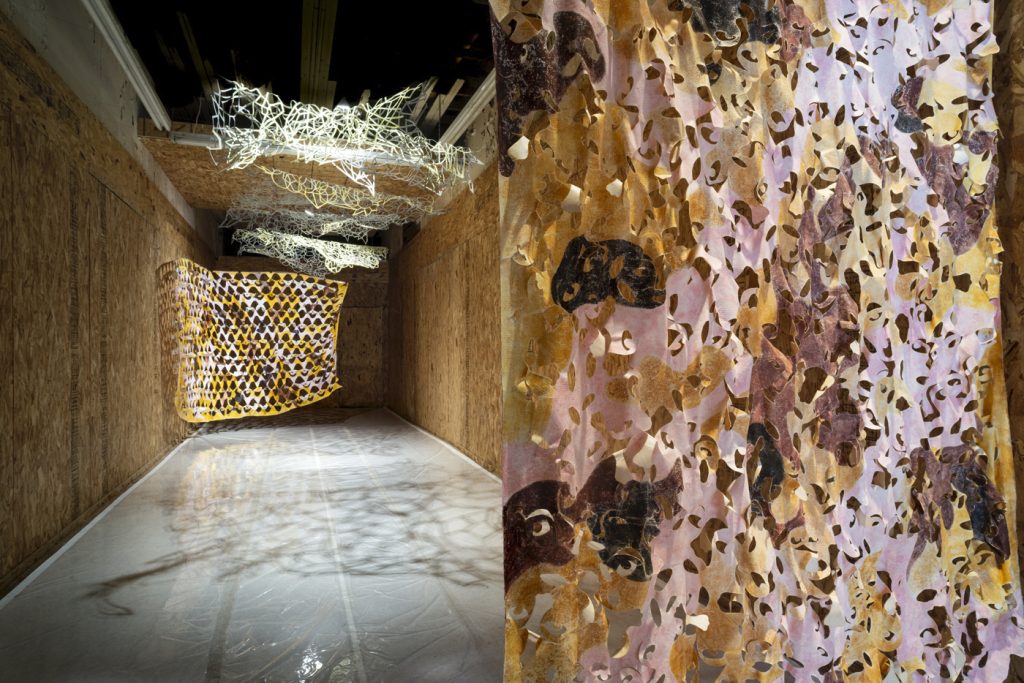 Five suspended handcut Tyvek (synthetic flashspun high-density polyethylene fibers) components, acrylic, glow in the dark gold, brown, and light pink paint