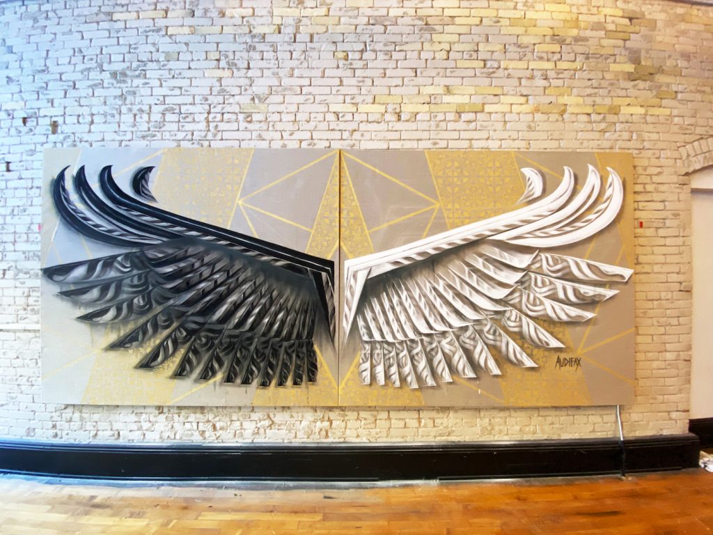Image of wings; left wing is black and right wing is white with a gold background