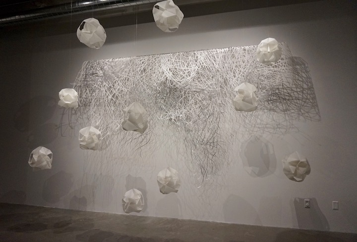 Abstract installation that looks like white clouds hanging in front of a white backdrop