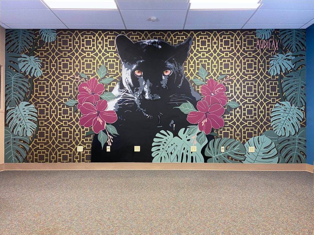 Image of mural showing black panther with pink/red flowers on both sides of it