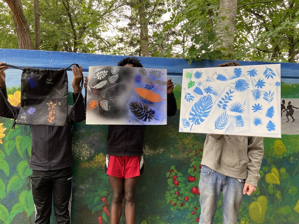 Teens holding up artwork they completed