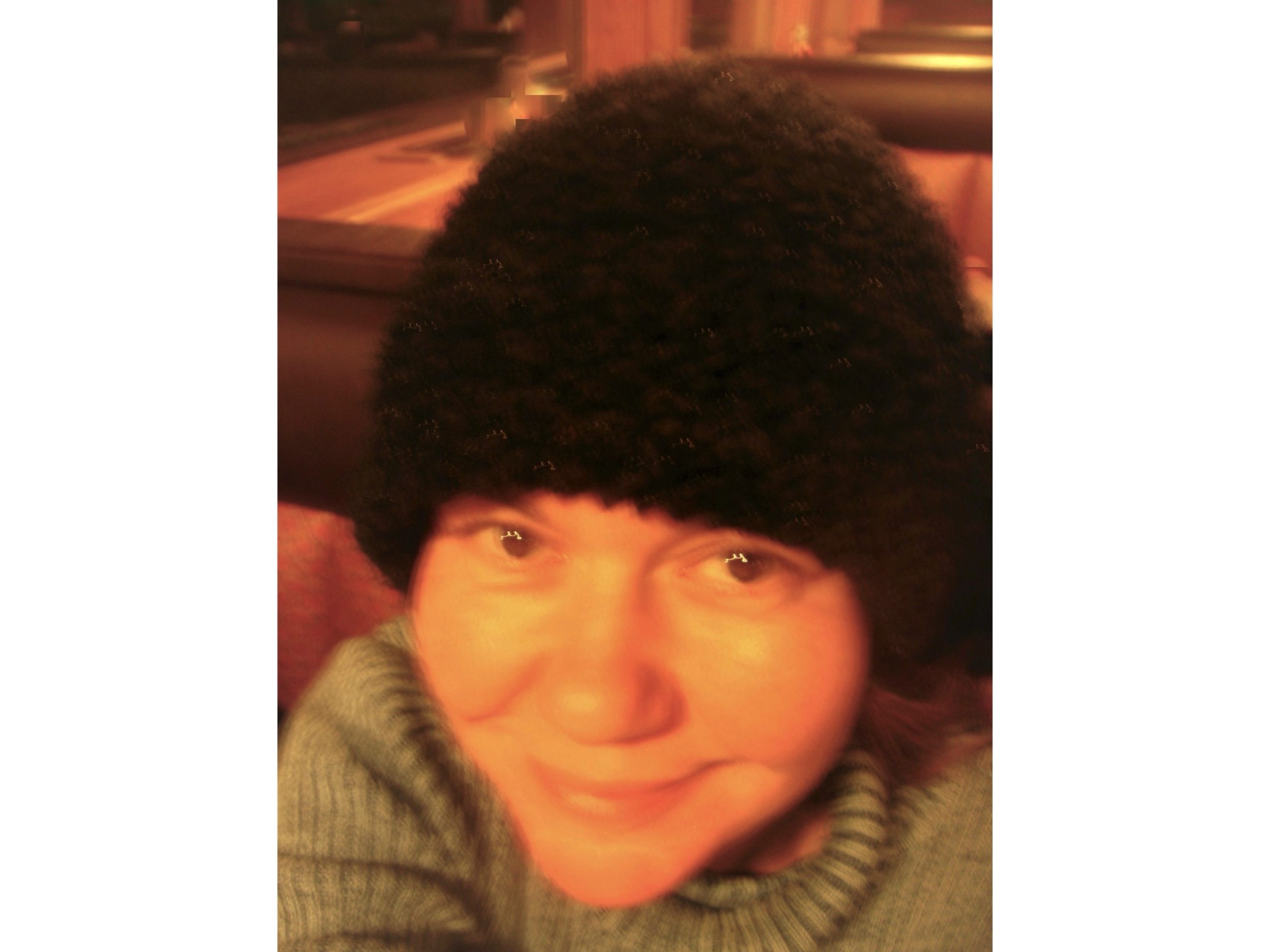Image of photo of artist with a hat on smiling at camera