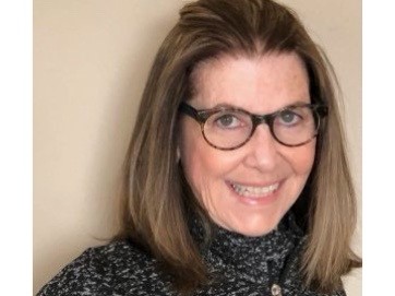 Image of photo of artist with shoulder-length brown hair and glasses smiling at the camera